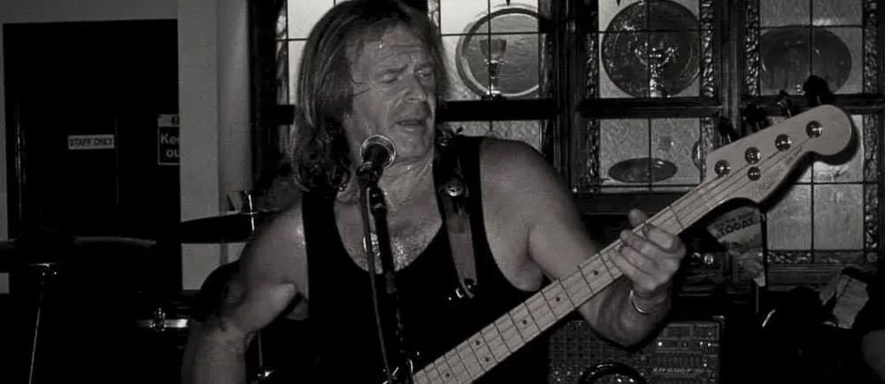 A bassist singing into the microphone during a live set