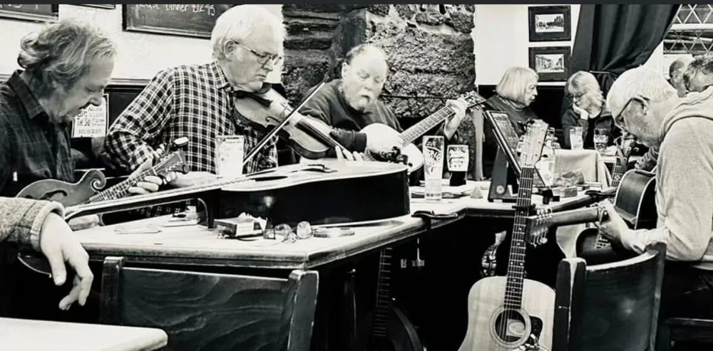 Musicians gathered around a table for a folk session, instruments in hand