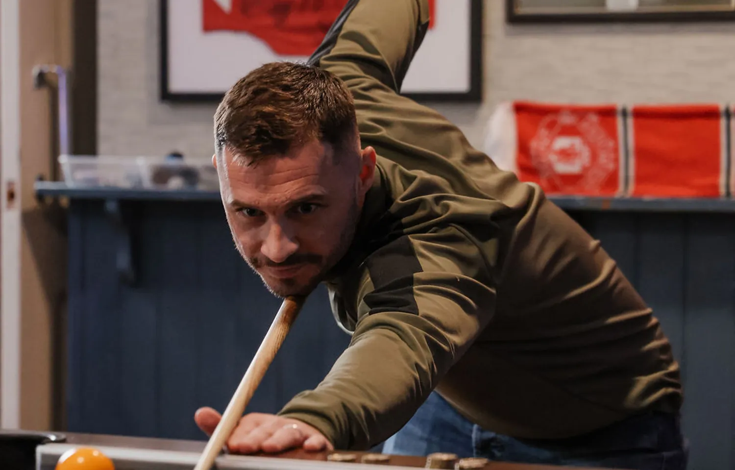 A game of pool in the bar, framed football shirts on the slate wall behind