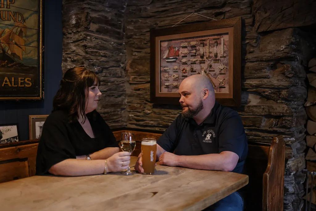 Two people sharing a drink at a table beside the slate wall