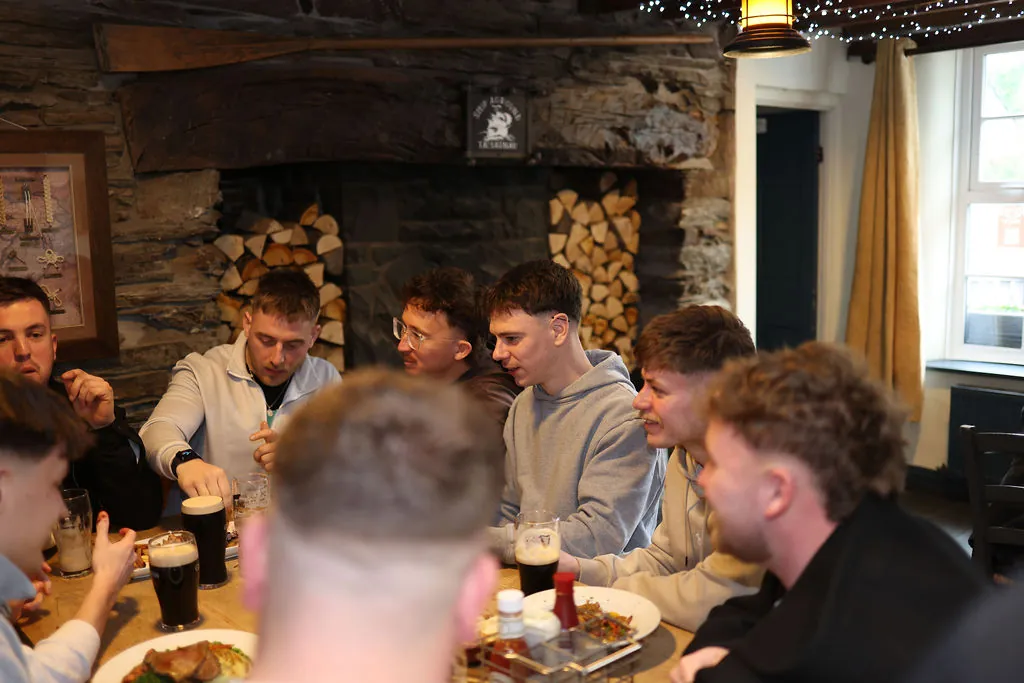 Friends gathered around a table with pints, talking and laughing